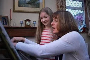 Alison at the piano with a young pupil