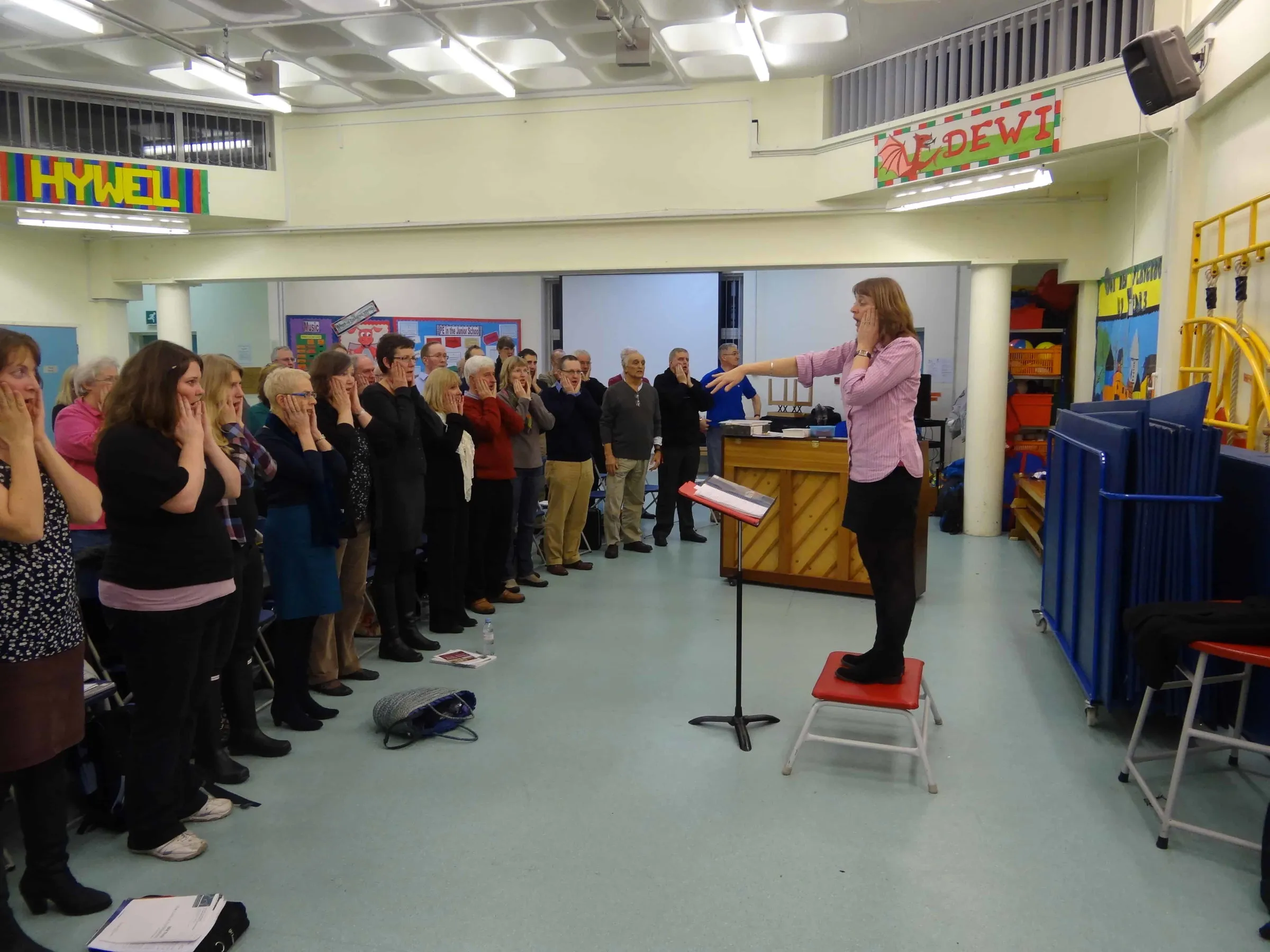 Alison conducting a choir rehearsal in a school hall
